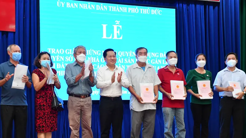 Chủ tịch UBND TP Thủ Đức Hoàng Tùng trao giấy chứng nhận quyền sử dụng đất, quyền sở hữu nhà ở và tài sản khác gắn liền với đất cho các hộ dân. Ảnh: VIỆT DŨNG