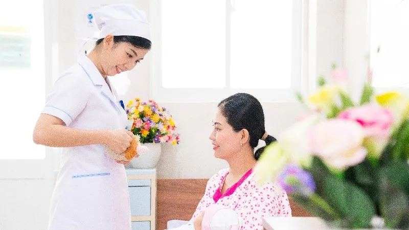 Nữ hộ sinh tư vấn cho sản phụ về tư thế cho con bú.