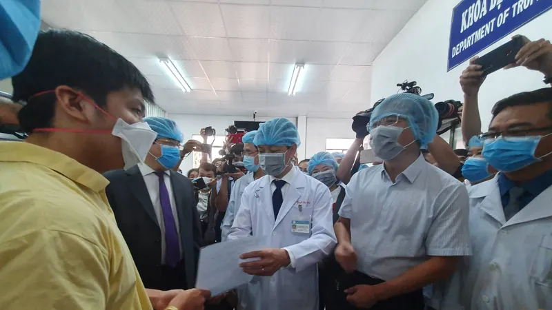 Bác sĩ Nguyễn Tri Thức, Giám đốc Bệnh viện Chợ Rẫy trao giấy xuất viện cho bệnh nhân Li Zichao (áo vàng)