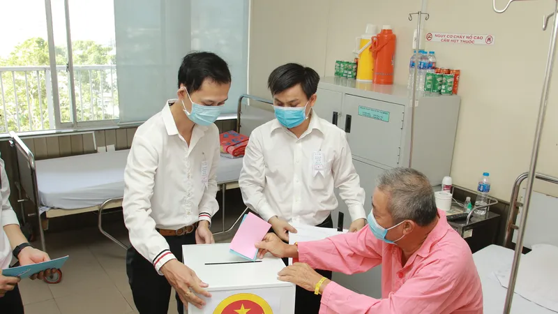 Thạc sĩ Lê Minh Hiển, Trưởng Phòng Công tác xã hội, Bệnh viện Chợ Rẫy cùng nhân viên UBND Phường 12, quận 5 mang thùng phiếu đến tận giường bệnh để bệnh nhân thực hiện quyền bầu cử
