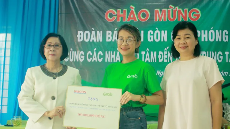 Bà Lý Việt Trung, Phó Tổng Biên tập Báo SGGP (bên phải) cùng đại diện Công ty TNHH Grab trao hỗ trợ 100 triệu đồng cho bà Nguyễn Thị Thu Hà, Giám đốc Trung tâm Võ Hồng Sơn. Ảnh: NGUYỄN TRANG