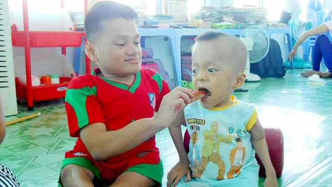 Huỳnh Đình Hạnh (bên trái) đút cơm giúp Lê Hoài Thương trong giờ ăn tại trung tâm
