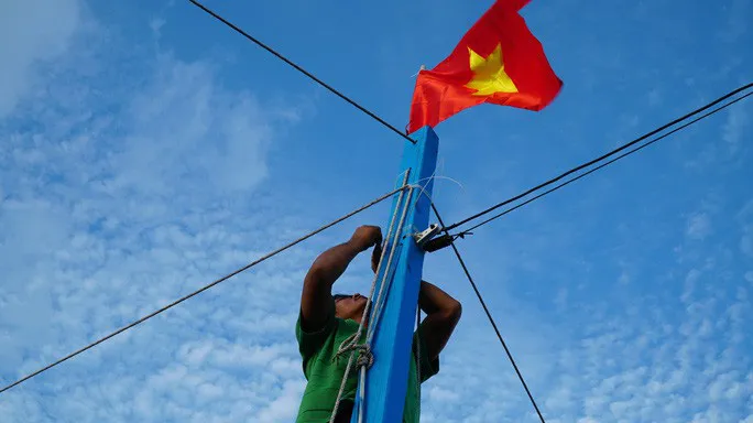  Ngư dân kiểm tra lại dây buộc Quốc kỳ trước khi cho tàu ra khơi. Ảnh: NLĐ 