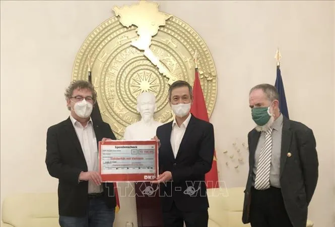  Chủ tịch Đảng Cộng sản Đức Patrik Köbele (trái) và ông Stefan Kühner (phải) trao số tiền quyên góp cho Đại sứ Nguyễn Minh Vũ. Ảnh: TTXVN