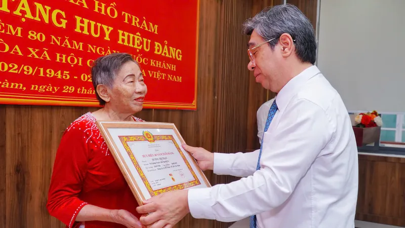 Đồng chí Nguyễn Phước Lộc, Phó Bí thư Thành ủy, Chủ tịch UBMTTQ Việt Nam TPHCM trao Huy hiệu 60 năm tuổi Đảng và tặng hoa chúc mừng đảng viên Dương Thị Xoan (xã Hồ Tràm)