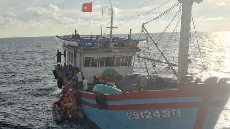 Các nhân viên tàu SAR 412 đưa xuồng cao su tiếp cận tàu cá và chuyển ngư dân Lê Thanh Hải sang tàu SAR 412 đưa về đất liền cấp cứu