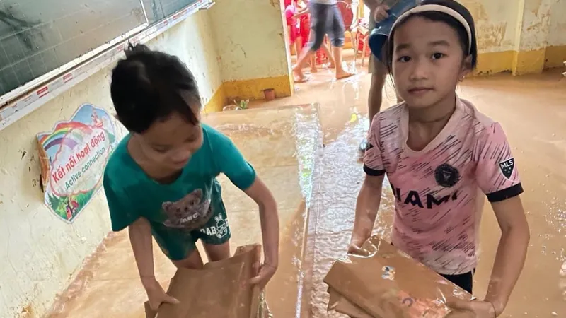 Học sinh điểm trường Tà Sỏi thuộc Trường tiểu học Châu Hạnh 2 (huyện Quỳ Châu, tỉnh Nghệ An) dọn sách vở trong đống bùn đất