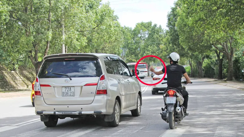 "Cò" mứt bám theo xe du lịch đưa danh thiếp (khoanh tròn) để đưa tới các cửa hàng kinh doanh đặc sản trên đường Phù Đổng Thiên Vương, TP Đà Lạt. Ảnh: SƠN CƯỜNG