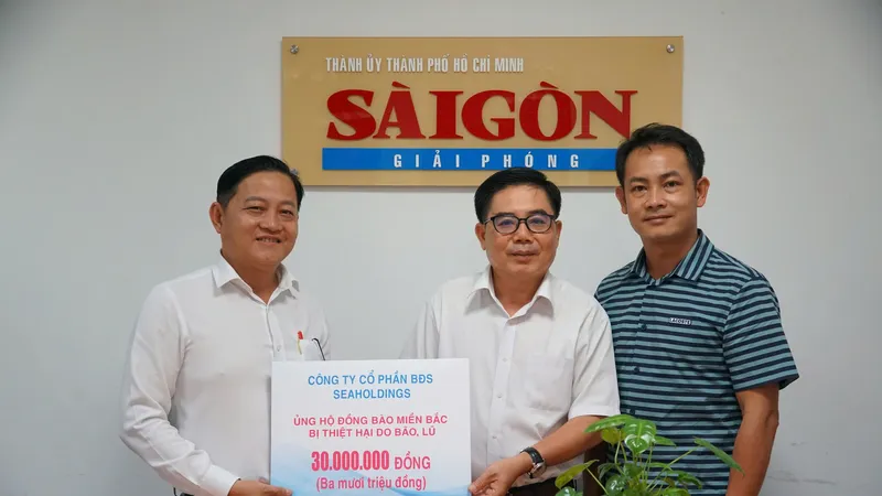 Ông Võ Thanh Hiền - Giám đốc truyền thông Seaholdings (bìa trái) trao bảng tượng trưng trị giá 30 triệu đồng hỗ trợ đồng bào miền Bắc khắc phục hậu quả bão lũ cho Báo Sài Gòn Giải Phóng. Ảnh: VIỆT NGA