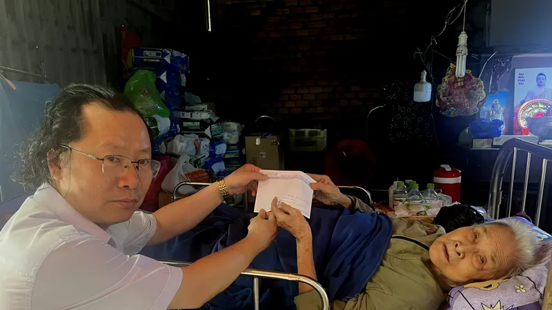Đại diện Báo Sài Gòn Giải Phóng trao tiền bạn đọc hỗ trợ cụ bà Vũ Thị Tân.