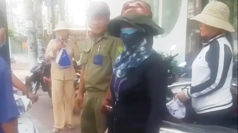 Bà Lê Thị Lại (che mặt) bị một số người chơi hụi phát hiện khi đang giao dịch tại một công ty bảo hiểm