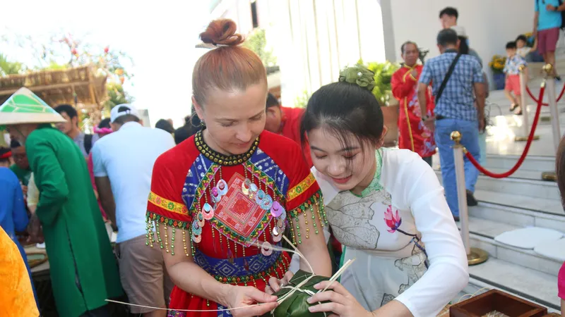 Khách nước ngoài thích thú tham gia thi gói bánh chưng