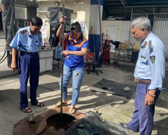 QLTT cùng nhân viên cây xăng đo lượng xăng trong bồn chứa
