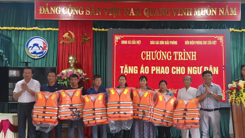 Phóng viên Báo SGGP và đại diện chính quyền địa phương trao áo phao cứu sinh tặng bà con ngư dân xã Cửa Việt, tỉnh Quảng Trị.