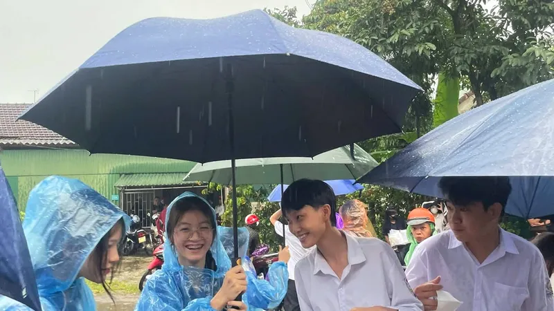 Đoàn viên, thanh niên dùng ô dù che mưa đưa đón thí sinh vào điểm thi 