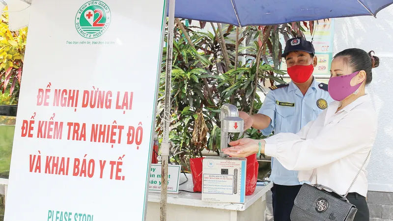 Nhân viên bảo vệ Trung tâm Y tế Thảo Điền, quận 2, TPHCM hướng dẫn người dân sát khuẩn trước khi vào trung tâm. Ảnh: HOÀNG HÙNG