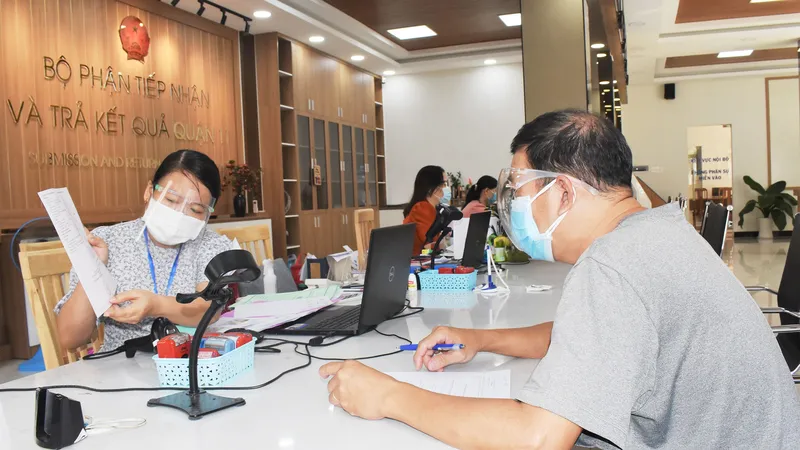 Cán bộ, công chức bộ phận tiếp nhận và trả kết quả quận 11 giải quyết hồ sơ cho người dân. Ảnh: ĐÌNH LÝ
