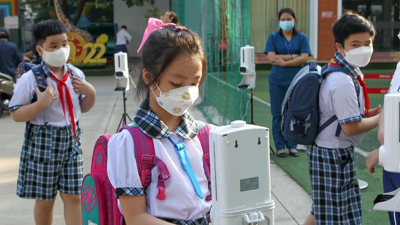 Học sinh Trường Tiểu học Lê Đức Thọ (quận Gò Vấp, TPHCM) vệ sinh tay trước sự giám sát của giáo viên khi vào cổng trường. Ảnh: HOÀNG HÙNG