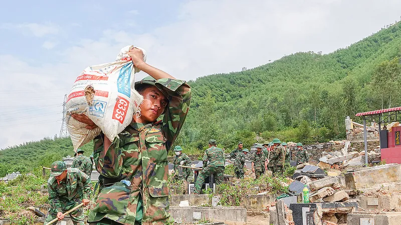Các chiến sĩ thuộc Trung đoàn 971 (Bộ Chỉ huy Quân sự TP Đà Nẵng) vác từng bao tải đất đá ra ngoài để tìm mộ bị vùi lấp do sạt lở. Ảnh: XUÂN QUỲNH