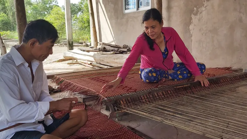 Hai vợ chồng bà Trần Thị Chính dệt những đôi chiếu cuối cùng để giao cho khách trước khi nghỉ tết. Ảnh: TẤN THÁI