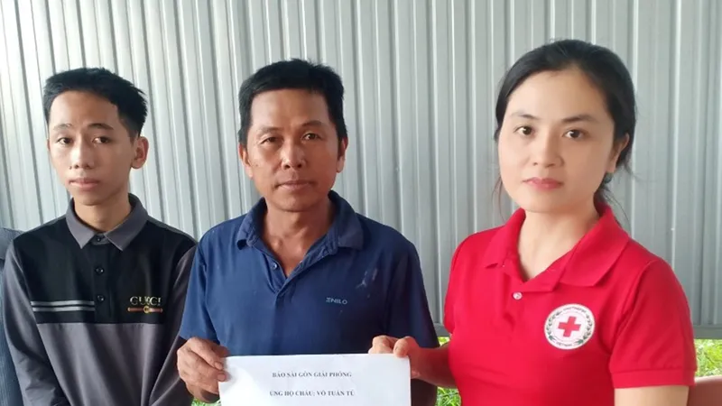 Em Võ Tuấn Tú và bố nhận 7,5 triệu đồng của bạn đọc Báo SGGP hỗ trợ. Ảnh: DƯƠNG QUANG