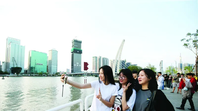 Các bạn trẻ chụp ảnh lưu niệm bên bờ sông Sài Gòn. Ảnh: DŨNG PHƯƠNG