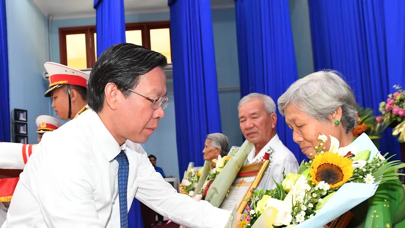 Chủ tịch UBND TPHCM Phan Văn Mãi trao danh hiệu Bà mẹ VNAH cho thân nhân mẹ. Ảnh: VIỆT DŨNG 