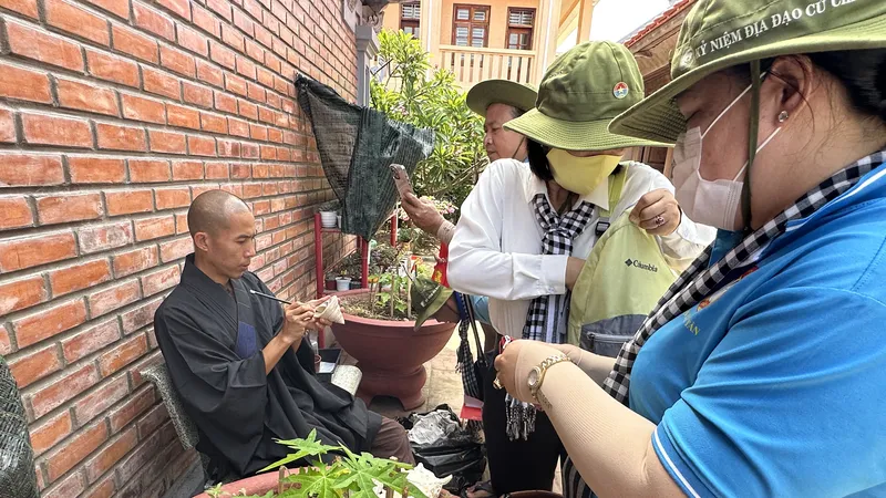 Đại đức Thích Nhuận Hiếu viết chữ lên vỏ ốc làm quà tặng cho khách từ đất liền ghé thăm chùa