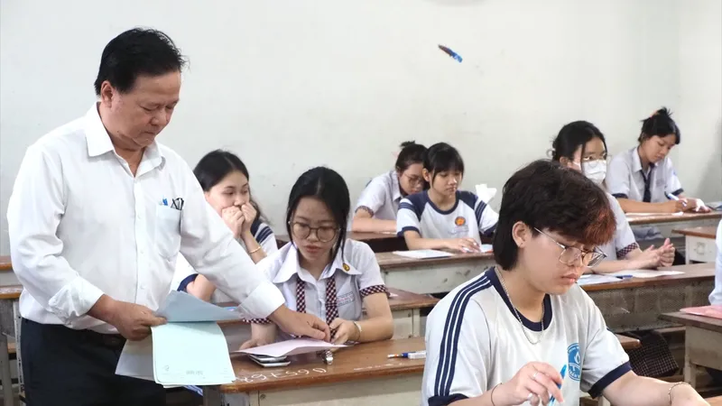 Cán bộ coi thi phát giấy nháp cho thí sinh tại một phòng thi. Ảnh: THU TÂM
