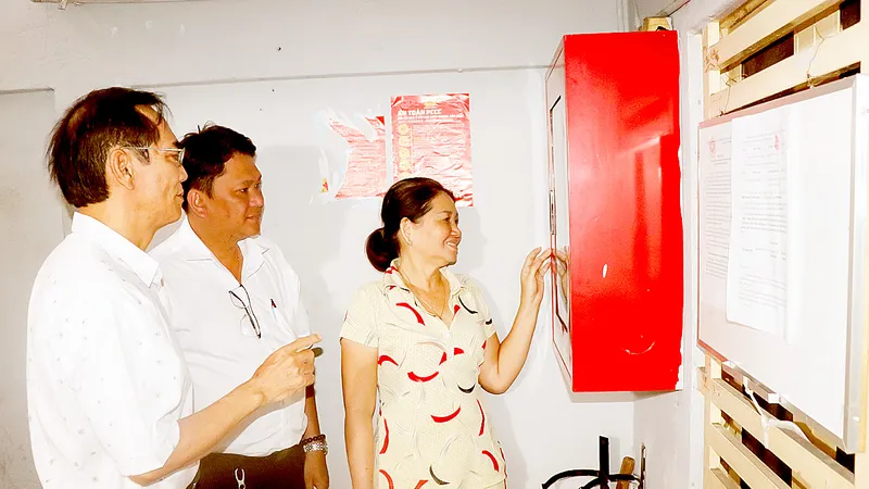 Ông Nguyễn Văn Quang (bìa trái), Bí thư Chi bộ Khu phố 4, phường 14, quận 5 hướng dẫn người dân chung cư tại khu phố sử dụng tủ PCCC. Ảnh: THÁI PHƯƠNG