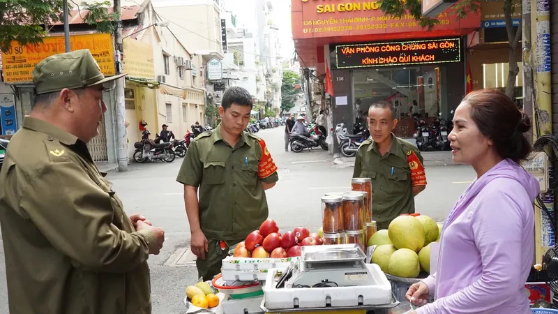 Lực lượng bảo vệ an ninh trật tự ở cơ sở phường Nguyễn Thái Bình, quận 1 trao đổi với người dân. Ảnh: THU HƯỜNG