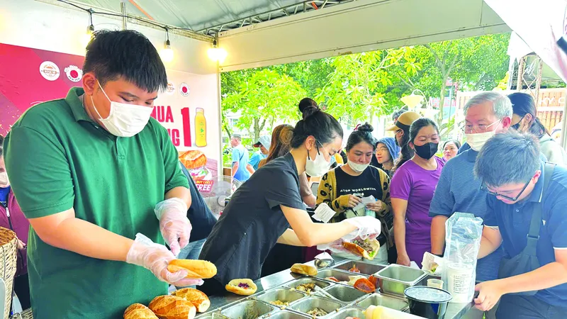 Người dân, du khách xếp hàng đợi mua và thưởng thức bánh mì Ảnh: QUỐC EM