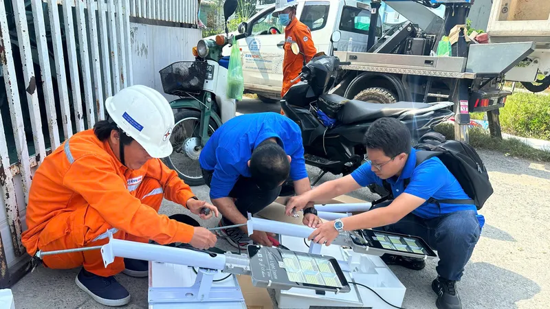 Anh Nguyễn Hoàng Thắng (bên phải) cùng đồng nghiệp thực hiện công trình thanh niên lắp đặt đèn năng lượng mặt trời cho các tuyến hẻm