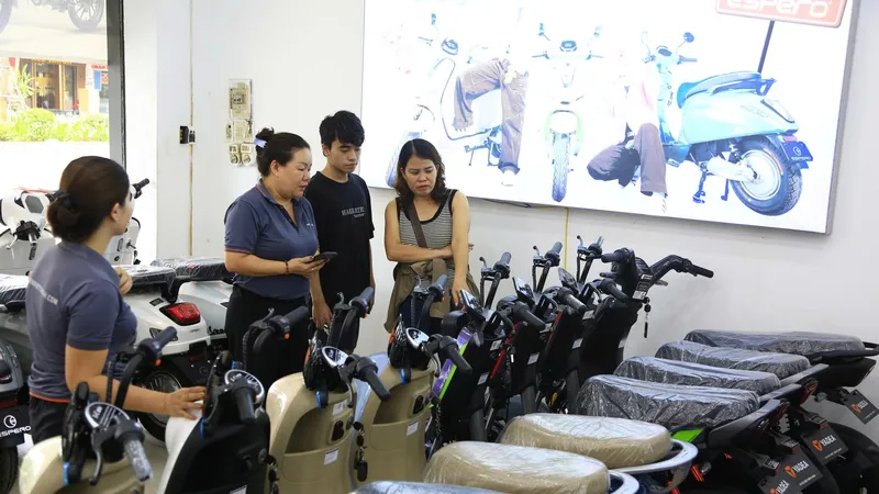 Chị Thu Phương (bìa phải) chọn mua xe máy điện cho con đi học tại một cửa hàng ở Xã Đàn (Hà Nội)