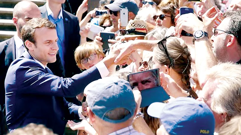 Tổng thống Pháp Emmanuel Macron (trái) gặp gỡ cử tri sau khi bỏ phiếu