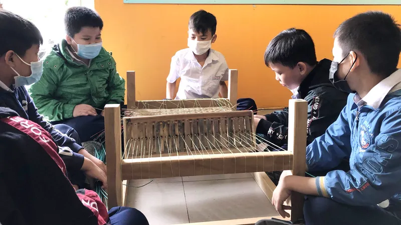 Các bạn nhỏ thích thú, chăm chú học theo từng công đoạn dệt chiếu thủ công