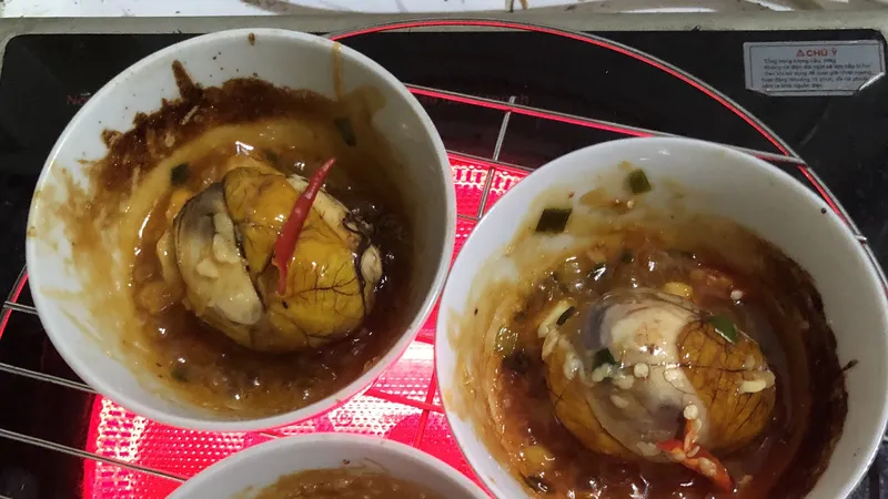 Trứng luộc xong lột vỏ, cho vô một cái chén nhỏ cho lên bếp nướng lửa nhỏ. Mỗi trứng cho 2 muỗng xốt. Nướng cho cạnh chén hơi cháy xém và xốt vừa sệt lại.
