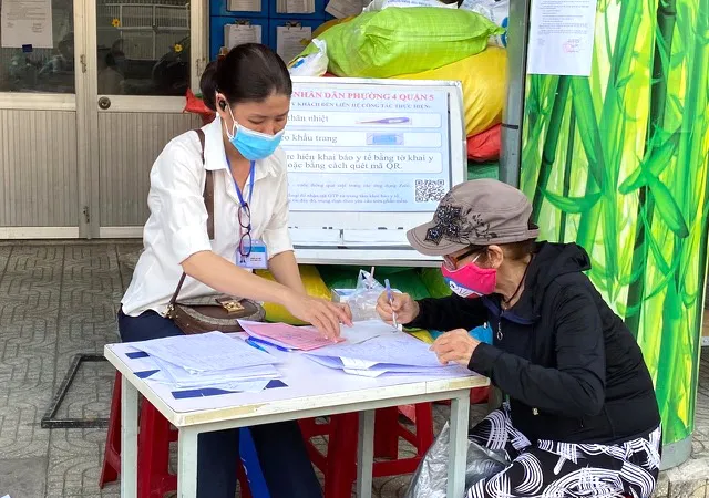 Cán bộ phường 4, quận 5 giải quyết chế độ chính sách hỗ trợ cho người dân. Ảnh: Cao Thăng
