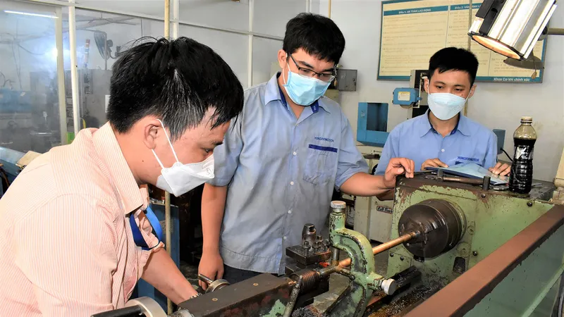 Thầy Lê Ngọc Tín (trái) hướng dẫn sinh viên năm cuối ngành Cắt gọt kim loại 1 thực hành trên máy
