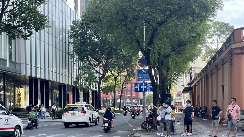 Các bạn trẻ và khách du lịch đón taxi phía ngoài cổng trung tâm thương mại ở TPHCM. Ảnh: HOÀNG HÙNG