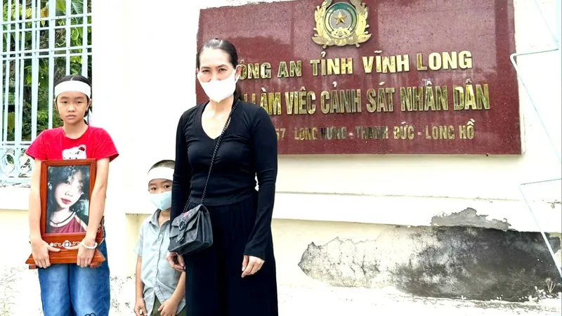 Bà Hiền cùng 2 con nhỏ và di ảnh bé Bảo Tr., trước Công an tỉnh Vĩnh Long