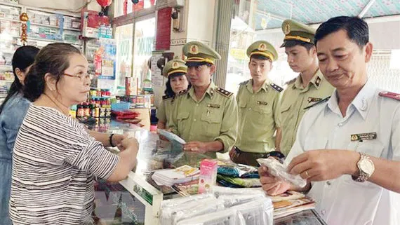 Lực lượng Quản lý thị trường kiểm tra, nhắc nhở các hiệu thuốc tân dược không tăng giá bán khẩu trang y tế. Ảnh: TTXVN