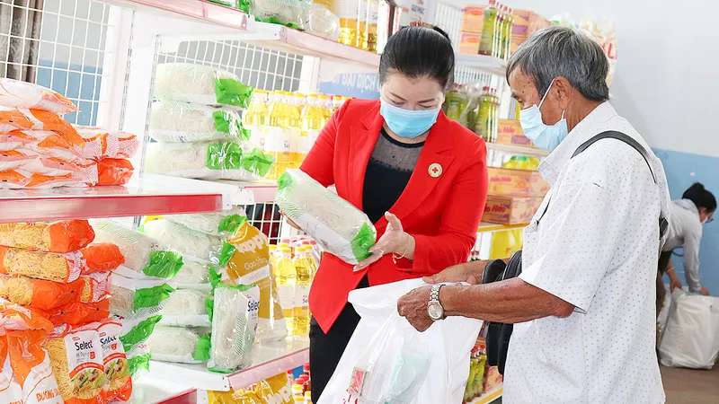 Tình nguyện viên giúp người khó khăn chọn nhu yếu phẩm tại phiên chợ nhân đạo tổ chức ở huyện Nhà Bè
