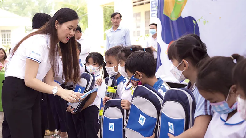 Bà Trần Kim Ngân - Giám đốc truyền thông Tập đoàn Xây dựng Hòa Bình đang trao cặp cho các em học sinh