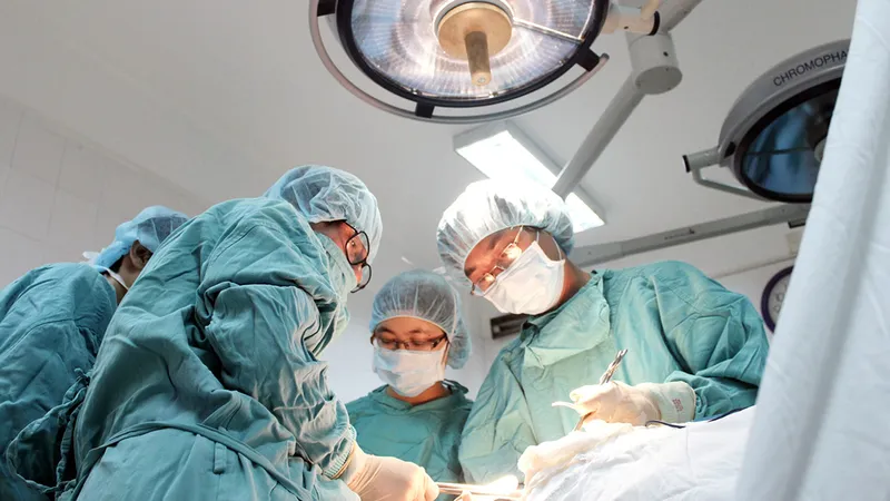 GS Cao Ngọc Thành (bìa trái) đang mổ chuyển giao kỹ thuật cho các bệnh viện khu vực miền Trung - Tây Nguyên