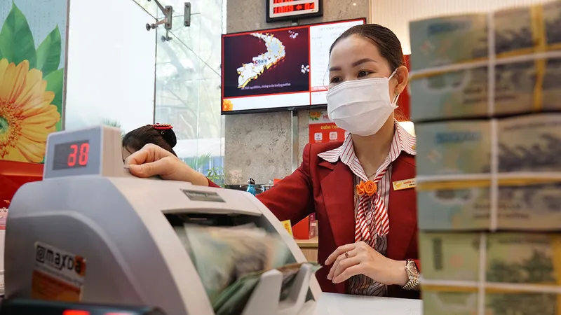 Nhân viên một ngân hàng đang kiểm tra tiền gửi tiết kiệm của khách hàng. Ảnh: HOÀNG HÙNG