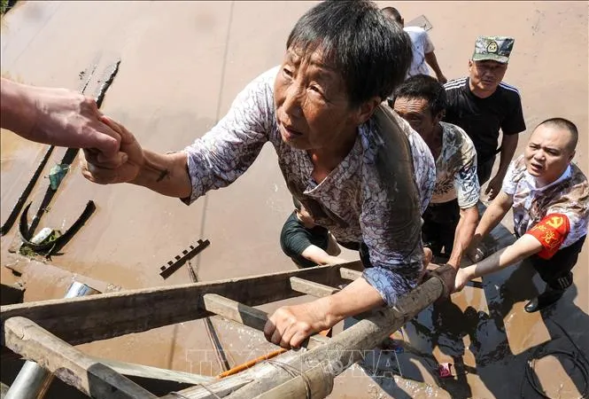 Nhân viên cứu hộ giúp sơ tán người dân khỏi các khu vực ngập lụt tại Dazhou, tỉnh Tứ Xuyên, Trung Quốc, ngày 12-7-2021. Ảnh: AFP/TTXVN