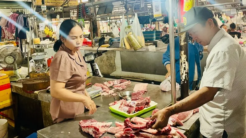 Người tiêu dùng chọn mua thịt heo tại chợ Tân Chánh Hiệp, quận 12, TPHCM, sáng 25-12