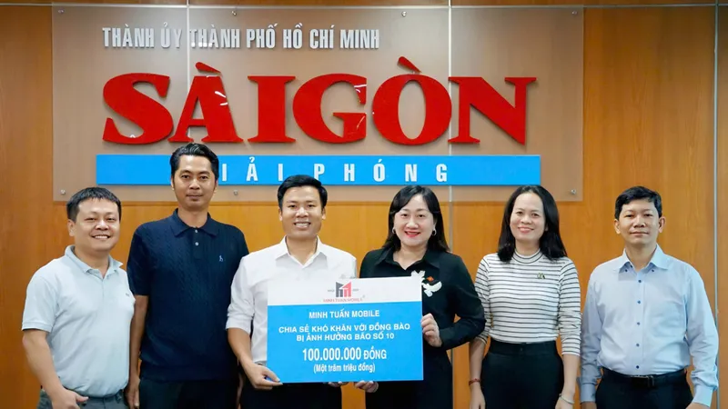 Phó Tổng biên tập Báo Sài Gòn Giải Phóng Bùi Thị Hồng Sương tiếp nhận bảng tặng 100 triệu đồng chia sẻ khó khăn với đồng bào bị ảnh hưởng bão số 10 từ ông Nguyễn Minh Tuấn, Giám đốc hệ thống Minh Tuấn Mobile (áo trắng giữa) . Ảnh: VIỆT NGA 