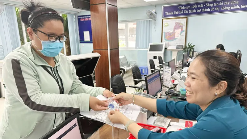 Công chức UBND phường Hiệp Bình Chánh, TP Thủ Đức (TPHCM) giải quyết hồ sơ cho người dân. Ảnh THU HƯỜNG